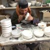 An old Palestinian man paints pottery at a local glass blowing business outside of Hebron.
