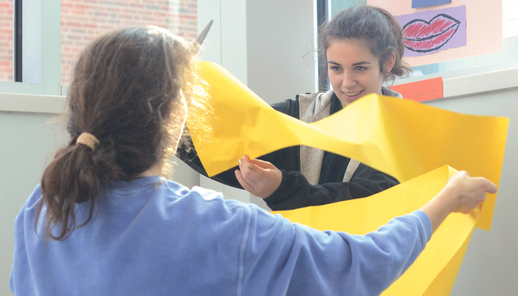 Freshmen Brigid Wentz and Gretchen Raedle play wiht the paper as they hang it up. Photo by Morgan Plunkett