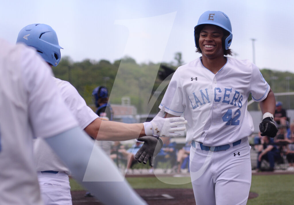 Senior John Mendy runs into the dugout while receiving high fives from his teammates after hitting a double giving the Lancers three runs in the fifth inning. Photo by Molly Miller