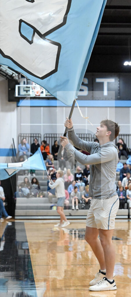Junior Tommy Trucksess holds the S flag in front of the sophomore section after running into the gymnasium at the beginning of the assembly. Photo by Molly McDermed